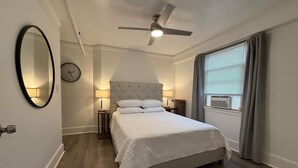 Una camera da letto con un letto grande, una ventola a soffitto, una sveglia e una finestra con tende.