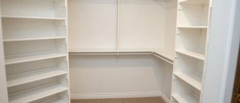A walk-in closet with multiple shelves and hanging space.