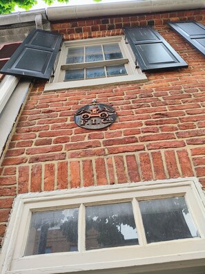 A brick building with a window and shutters, and a sign with a logo.