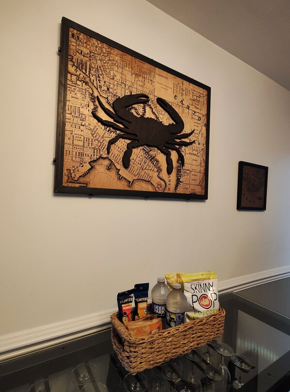 A wall with a large map artwork featuring a crab, a basket of snacks, and a bottle of soda.