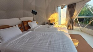 Camera da letto con due letti, una televisione e una finestra con tende.