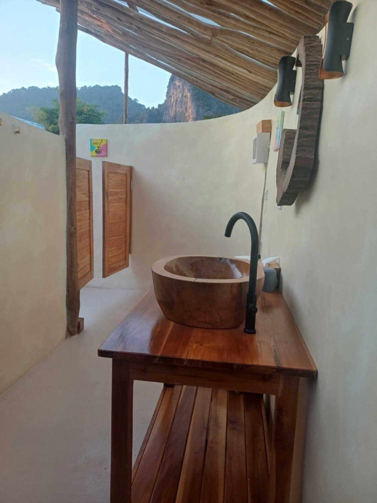 Un tavolo in legno con un lavandino ampio e un rubinetto nero, sullo sfondo di una parete bianca con soffitto in legno.