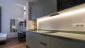 Una cocina moderna con estufa integrada, un lavamanos y una zona de comedor con una silla y mesa.