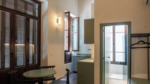Habitación compacta y bien iluminada con comedor, sofá y kitchenette.