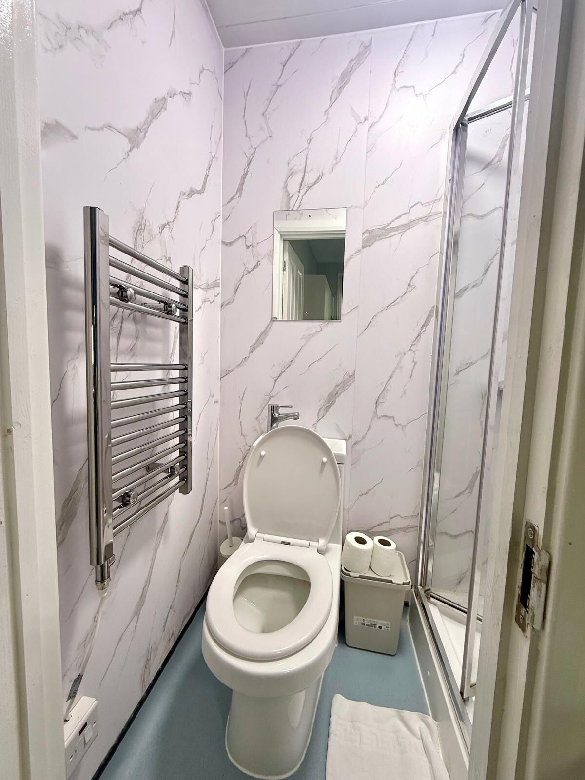 Un baño con inodoro, ducha y toallero.