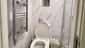 A bathroom with a toilet, a shower, and a towel rack.