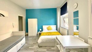 A compact room with a bed, a desk, a wardrobe, and a window.