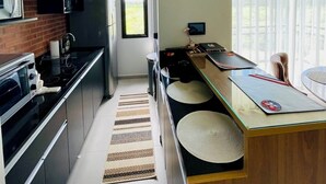 Een moderne keuken met een Pilsen bord, een koelkast, een magnetron en een fornuis.