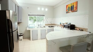 Una cocina moderna con encimera de mármol, electrodomésticos de acero inoxidable y un ventanal que proporciona luz natural.