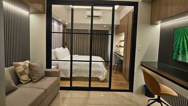 A modern bedroom with a large bed, a desk, and a TV. - Luxury condo with gym,WiFi,NETFLIX at Park Mckinley West, Venice, SM Aura BGC (Taguig)