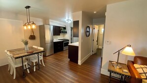 A modern kitchen with a refrigerator, oven, and dining area with a table and chairs. - Charming Bungalow 2 in lovely Spearfish with WiFi, AC (Spearfish)