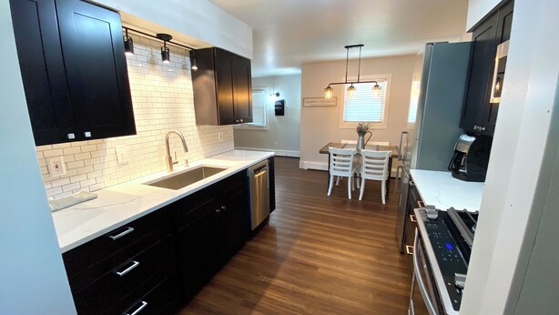 A modern kitchen with dark cabinetry, a white countertop, and a built-in dishwasher. - Charming Bungalow 2 in lovely Spearfish with WiFi, AC (Spearfish)