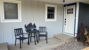A porch with two chairs and a small table, a door, and a window. - Charming Bungalow 2 in lovely Spearfish with WiFi, AC (Spearfish)