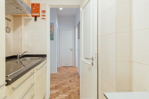 A kitchen with a sink, cabinets, and a herringbone-patterned wooden floor leading to a door. - DOWNTOWN AQUARELLE with AC by VACATIONY (Oporto)