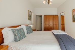 Quarto de hotel com uma cama grande, guarda-roupa de madeira e um quadro na parede.