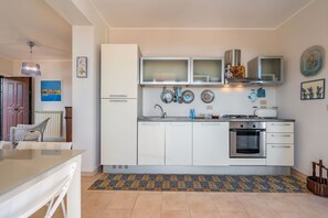 Een koelkast, een oven, een kookplaat, kookgerei, borden en bestek