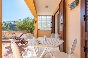 A balcony with a table, chairs, and a view of buildings.