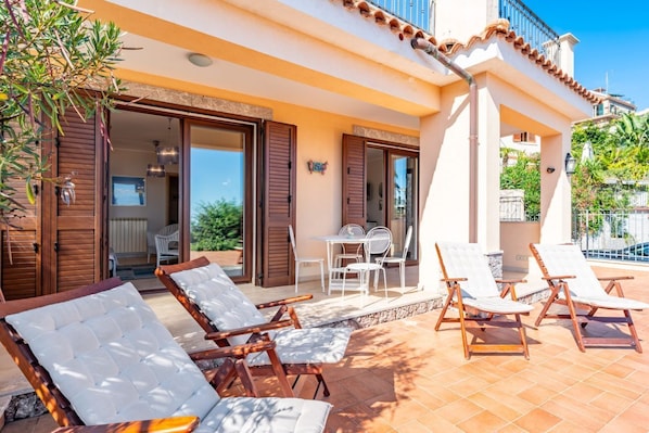 A villa with a patio, outdoor seating, and a view of the surrounding landscape.
