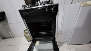 An open oven with a timer set to 0 minutes, a gas burner, and a gas cylinder in the kitchen.