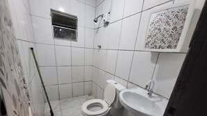 A small, tiled bathroom with a toilet, sink, and shower.