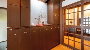 A hotel lobby with a wooden reception desk, numbered lockers, and a glass door leading to a well-lit interior. - Cottage Alice (Hachimantai)