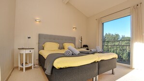 A modern bedroom with a large bed, bedside tables, and a view of trees through a balcony. - Beautiful home in Sainte Maxime (Sainte Maxime)
