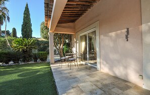 A covered patio with a table and chairs, a glass door, and a well-maintained garden with various plants. - Beautiful home in Sainte Maxime (Sainte Maxime)