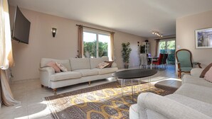 A spacious living room with a sofa, a coffee table, and a dining area with chairs. - Beautiful home in Sainte Maxime (Sainte Maxime)