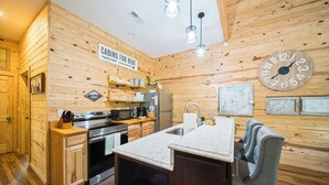 Ein Holzblockhaus-Interieur mit Küche, Holzwänden, einer Uhr und einem Schild, das auf zu vermietende Hütten hinweist.