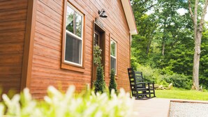 A wooden cabin with a porch, a bench, and a small tree. - Bear's Den Retreat • Hot Tub • Soak Tub • Dog Friendly • Hocking Hills Cabin (Logan)