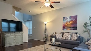 A modern living room with a sofa, a coffee table, and a TV on a cabinet.