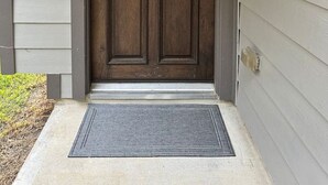 A front door with a wreath, a keypad lock, and a doormat.