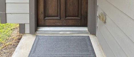 A front door with a wreath, a keypad lock, and a doormat.