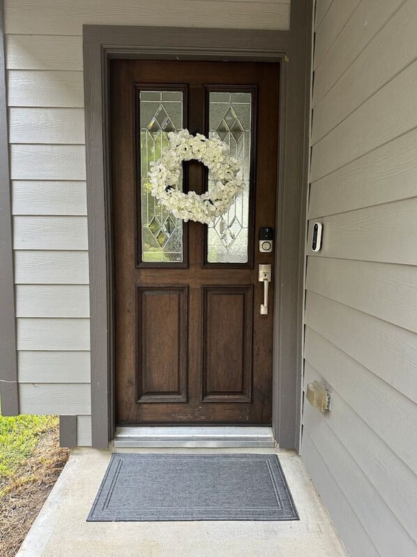 A front door with a wreath, a keypad lock, and a doormat.