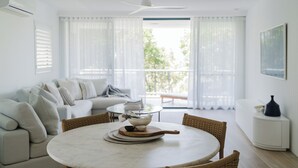A modern living room with a round marble table, a sofa, and a dining area.