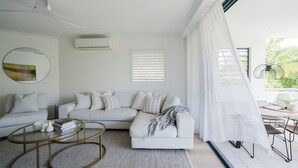A modern living room with a sectional sofa, a glass coffee table, and a view of the outdoors.