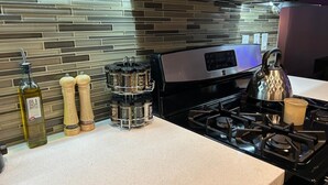 A kitchen with a modern stove, a stainless steel kettle, and a spice rack. - Downtown LA - Free Parking- Legends Loft! (Vernon)