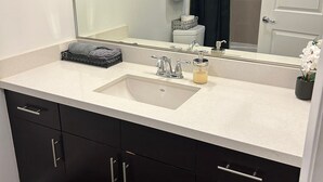 A bathroom with a white sink, dark cabinets, a mirror, and a shower curtain. - Downtown LA - Free Parking- Legends Loft! (Vernon)
