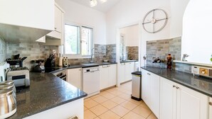 Une cuisine moderne avec des meubles blancs, un plan de travail noir et un pare-feu en pierre.