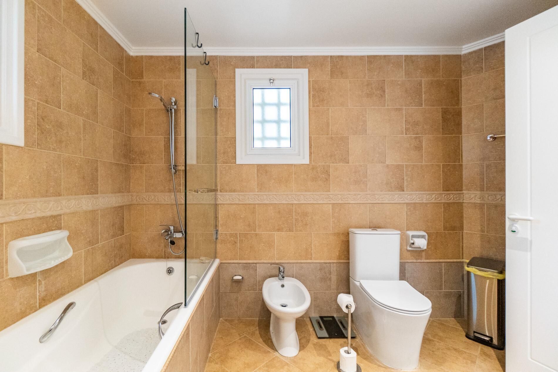 A bathroom with a bathtub, bidet, toilet, and a glass shower enclosure.