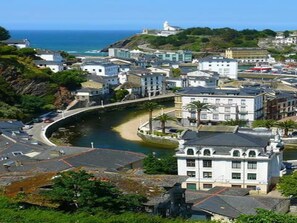 A coastal town with a prominent white building, a curved road, and a lighthouse in the background. - Room in Guest Room - Lovely Double Room With Private Bathroom (Valdes)