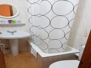 A bathroom with a white sink, a mirror, a toilet, and a shower curtain with a circular pattern. - Room in Guest Room - Lovely Double Room With Private Bathroom (Valdes)