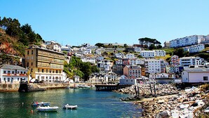 A coastal town with buildings along the waterfront, boats docked near the shore, and a rocky breakwater. - Room-cozy Double Room With Shared Bathro (Valdes)