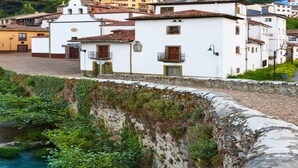 A historic town with white buildings and a stone wall overlooking a clear blue river. - Room-cozy Double Room With Shared Bathro (Valdes)