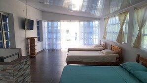 Una habitación con dos camas, televisión y un ventanal grande.