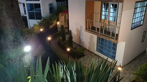 Un edificio moderno con balcón, un pequeño jardín y un sendero.