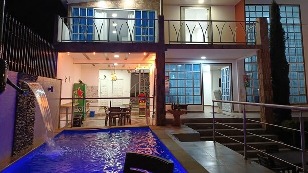 Un área de piscina interior con varios niveles, una cascada, una escalera y una zona de estar.