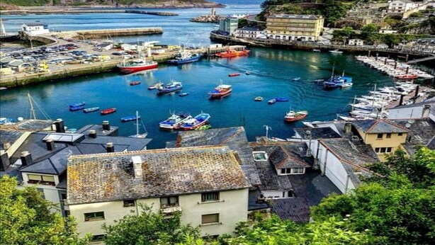 Una cittadina costiera con un porto turistico pieno di barche, circondata da edifici e vista sul mare.