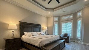 A bedroom with a large bed, nightstands, a bench, and a chair.