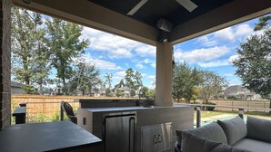 An outdoor kitchen area with a built-in sink, cabinets, and a grill.
